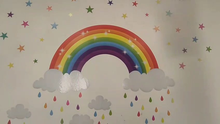 Mural de un arcoíris con nubes y gotas de colores
