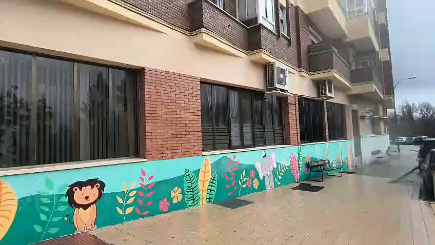 Mural de selva con un león y plantas tropicales en la fachada